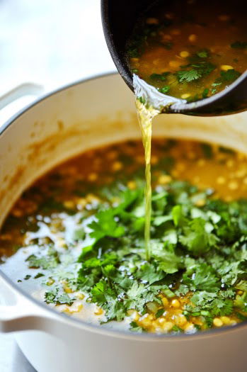 A top-down view of the pot as a cornstarch mixture, combined with half-and-half, is stirred into the chili. The remaining half-and-half is added, thickening the chili to a creamy consistency. The scene captures the rich, creamy texture of the chili as it thickens.