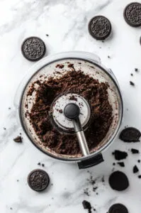 This image shows Oreo cookies being finely processed in a food processor until they are completely crushed.