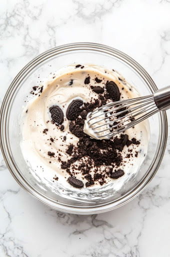 This image shows crushed Oreo cookies being mixed with milk and baking powder until a smooth batter forms.