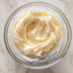 Top-down view of the mixing bowl as the frosting consistency is managed and adjusted and cheese glaze is ready to be used.