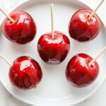 this image shows sweet candy apples ready to be served in a white plate