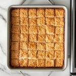 Top-down view of the baking pan with the toffee-coated graham crackers in the oven, bubbling and turning golden brown as they bake.