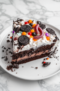 Top-down view of a slice of graveyard Oreo pudding cake on a white plate. The slice reveals layers of creamy filling and Oreo crumbs, topped with a Nutter Butter tombstone and candy pumpkins for decoration.