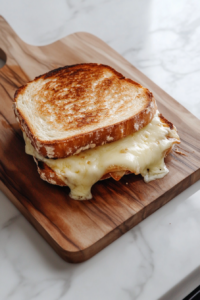 Top-down view of a fully toasted sandwich on a wooden cutting board.