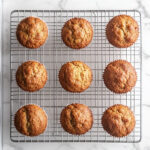 this image show freshly baked golden brown vegan morning glory muffins on a cooling rack