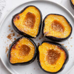 This image shows the final dish, warm slices of acorn squash sprinkled with brown sugar and butter, ready to be served.