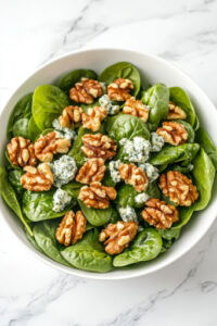 This image shows the toasted walnuts being placed on top of the salad as a final garnish.