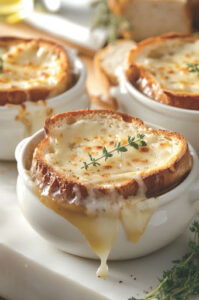 This image shows cheese-topped bread slices in the oven. The cheese is melting, bubbling, and turning golden brown.