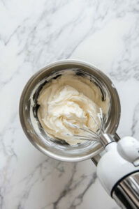 This image shows a stand mixer bowl with shortening and vanilla being beaten together with the paddle attachment until creamy.