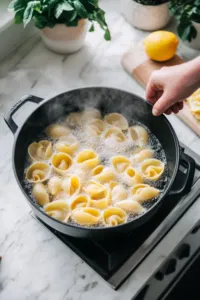 The oven preheats to 350°F (175°C), with a 9x13-inch baking dish placed on the white marble cooktop, ready for the stuffed shells. A digital timer is set to track the baking time.