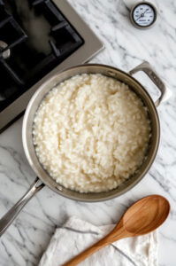 This image shows the rice being stirred into the butter and oil mixture, evenly coating each grain.