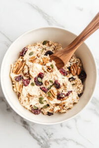 This image shows the wet ingredients being poured into the bowl containing the oat mixture, ready to be stirred together.