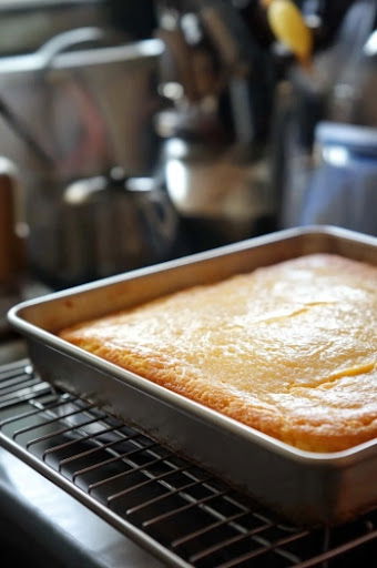 This image shows the pineapple mixture being evenly spread over the cooled cake while it’s still in the 9x13" pan.