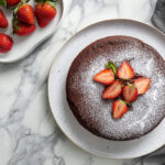 This image shows a soy-free cake beautifully garnished with fresh, thinly sliced strawberries arranged on top.