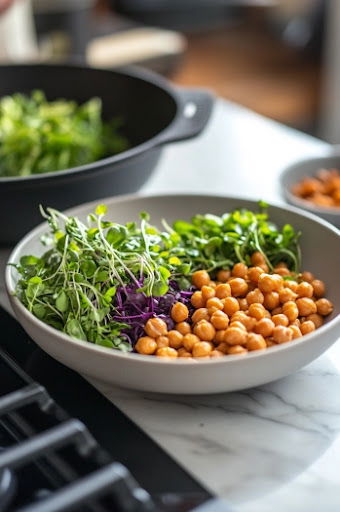 This image shows microgreens and roasted chickpeas being sprinkled over the polenta and mushrooms, providing added texture and a burst of color.