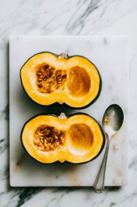 This image shows two acorn squash halves with their seeds and stringy insides removed, ready to be roasted.