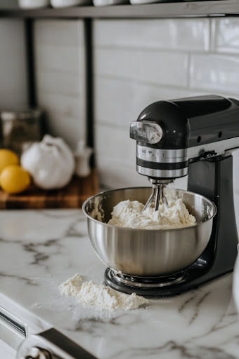 This image shows the KitchenAid stand mixer with the dough hook attachment, mixing the dough on speed 2 for one minute.