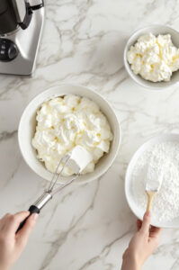 This image shows a large mixing bowl with buttermilk, milk, eggs, and melted butter being whisked together until smooth.