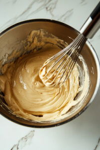 This image shows a bowl with the dry ingredients, milk, and eggs being whisked together. The batter is becoming smooth and lump-free as the whisk moves through it.