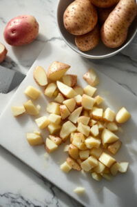 this image shows Peeled potatoes chopped into ½-inch cubes, ready for cooking.