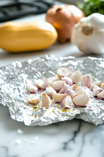 This image shows the seasoned squash halves being placed cut side down on a baking sheet, prepared for roasting.