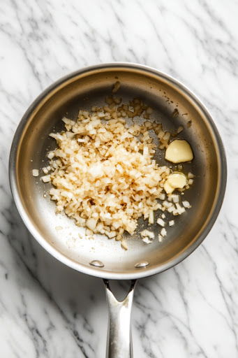 This image shows a skillet with sautéed onions and garlic, creating a flavorful base for the risotto.