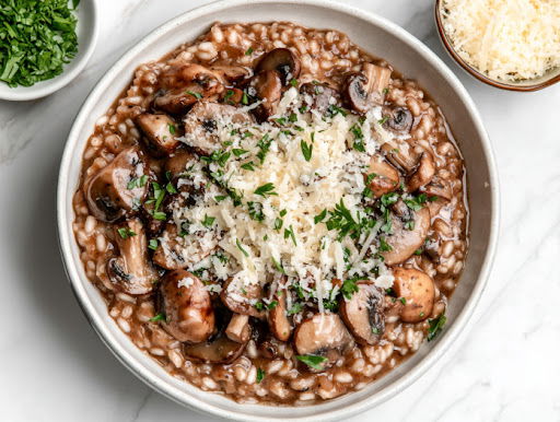 This image shows the dish being served, topped with the remaining sautéed mushrooms and garnished with fresh parsley, with extra grated cheese offered on the side.