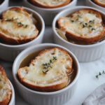 This image shows a bowl of French onion soup, topped with golden, cheesy bread slices. The rich, fragrant broth and onions are ready to be enjoyed.