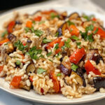 This image shows a vibrant dish of wild rice pilaf, filled with roasted vegetables, cranberries, and pecans, ready to be served