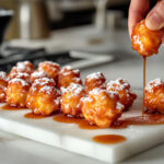 This image shows a white plate with freshly made apple fritters, golden brown and glazed, ready to be served.