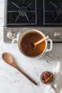 This image shows the Dutch oven with the heat reduced to low, gently simmering the mulled cider without reaching a full boil.