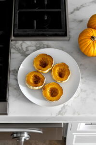 This image shows the roasted acorn squash halves being sliced into thirds after baking, with golden edges showing.