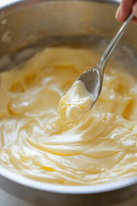 This image shows vanilla extract being stirred into the melted butter and marshmallow mixture, creating a smooth blend.