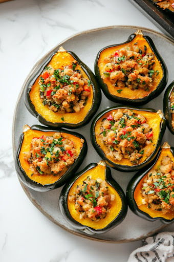 This image shows the finished stuffed acorn squash with quinoa served on a white plate, ready to be enjoyed. The squash is golden and the stuffing is crispy and flavorful.