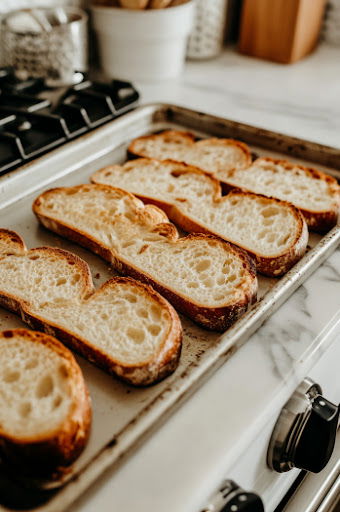 This image shows toasted slices of bread being flipped, then sprinkled with a mix of grated Gruyère and Parmesan cheese.