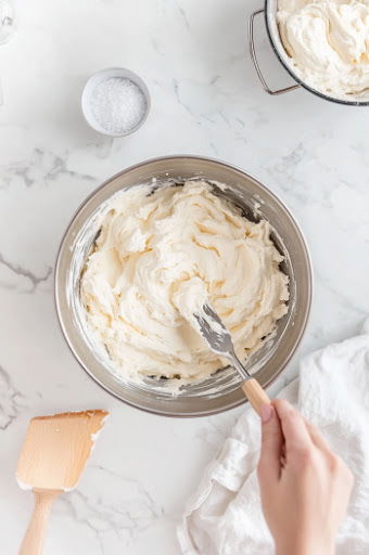 This image shows milk being used in the stand mixer to adjust the consistency of the frosting.