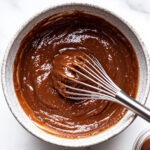 This image shows a whisk being used to stir the apple butter, giving it a smooth, creamy consistency.