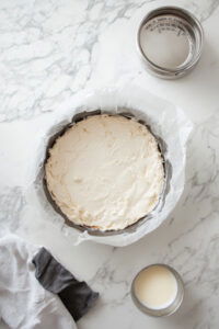 This image shows a baking pan being wrapped with a long piece of aluminum foil, extending above the rim for easy removal.