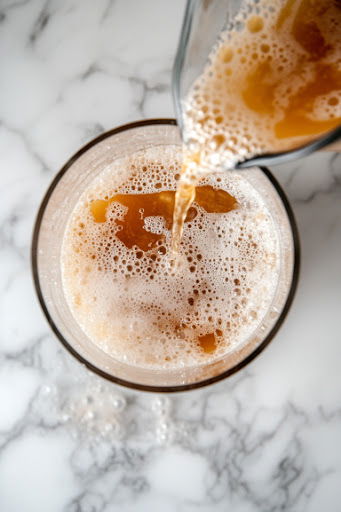 This image shows a pitcher of pina colada sangria being poured in a glass