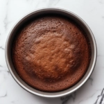 The pan in the oven at 320°F on the white marble cooktop, baking for 30 minutes. Once fully cooled in the pan, the cake is ready to be sliced thinly and served.