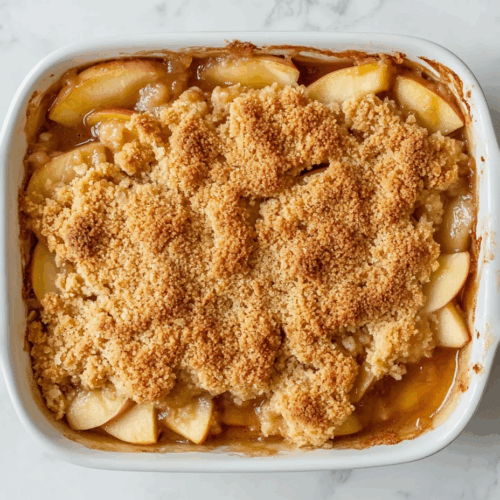 The freshly baked Apple Crisp rests on the white marble cooktop with steam rising, ready to be served.