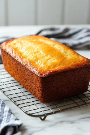 The baked clementine yogurt olive oil cake resting on a wire rack placed over the white marble cooktop, cooling and ready to be sliced and served.