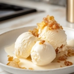 The frozen ginger ice cream desserts unmolded onto a plate on the white marble countertop, garnished with crystallized ginger and drizzled with ginger syrup for an elegant presentation.