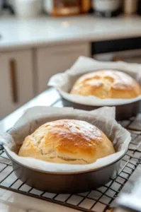 Each dough square is tightly rolled like a jelly roll on the white marble cooktop, with edges pinched to seal. The logs are rolled under palms to form uniform rounds.