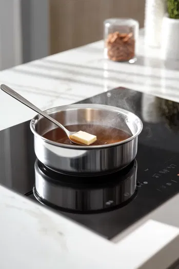 Butter and brown sugar boiling in a saucepan on a stovetop, stirred constantly to form the caramel mixture for the crackers