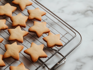 Unbaked cookie shapes are neatly arranged on a parchment-lined baking sheet resting on the white marble cooktop. The tray is ready to be transferred into a preheated oven for baking