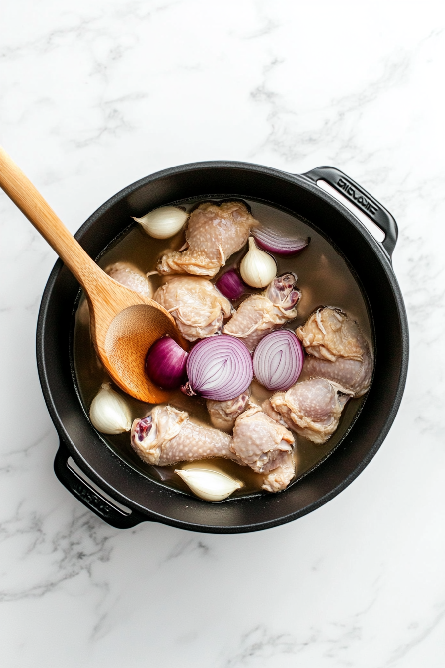 In a large pot, combine chicken, sliced onion, garlic, and enough water to cover; bring to a boil and simmer until chicken is cooked (about 45 minutes).