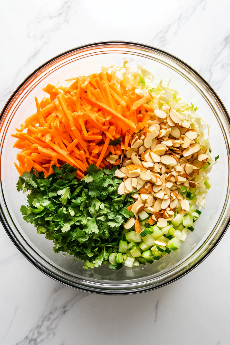 In a large bowl, combine coleslaw mix, shredded chicken, carrots, cilantro, green onions, and toasted almonds.
