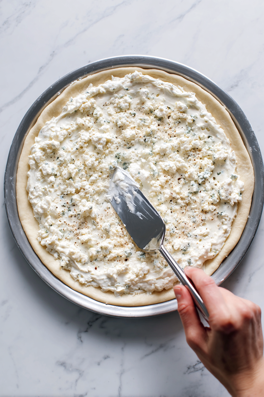 Spread blue cheese dressing over the pizza crust.