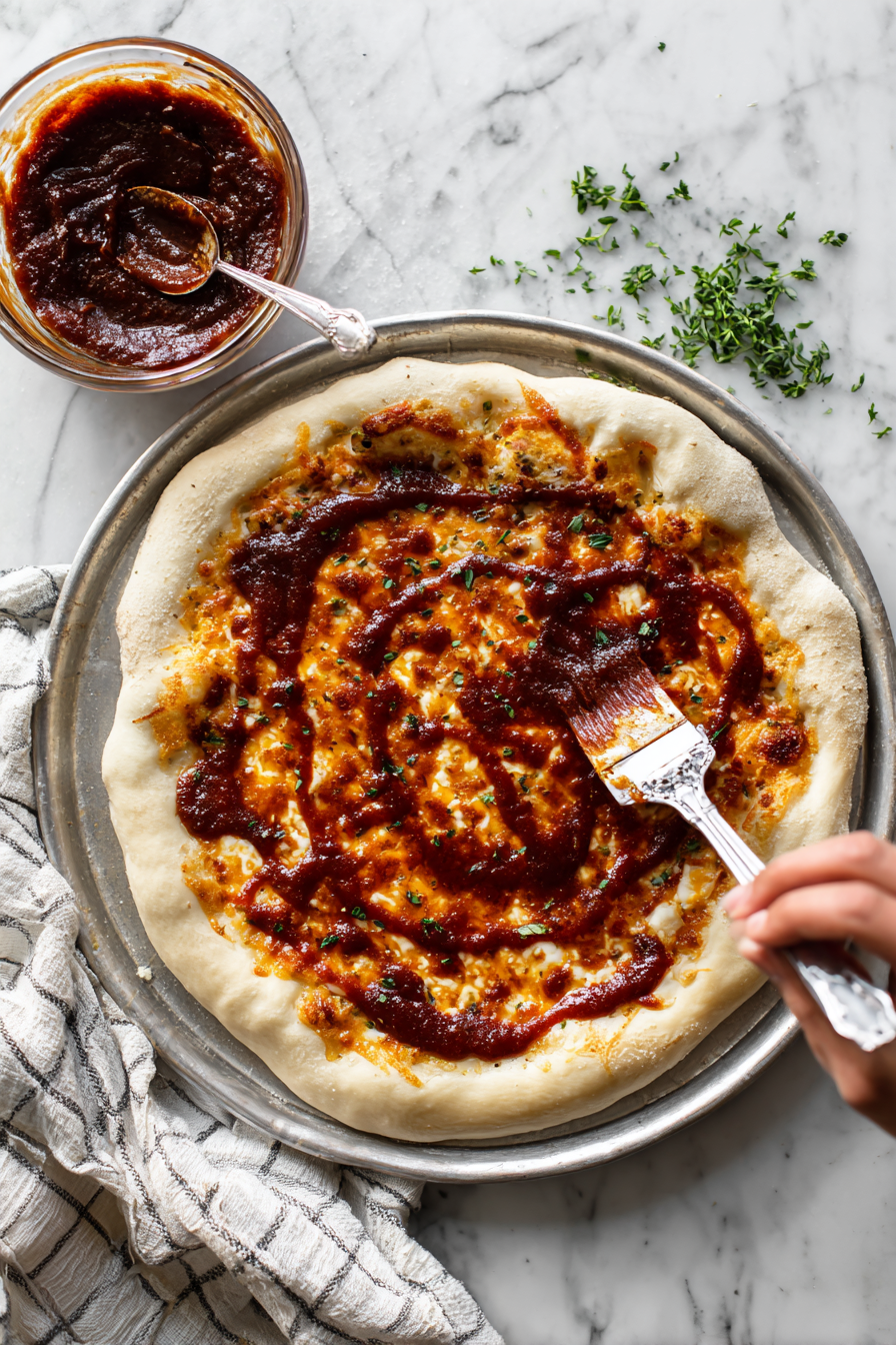 Spread BBQ sauce evenly over the crust.